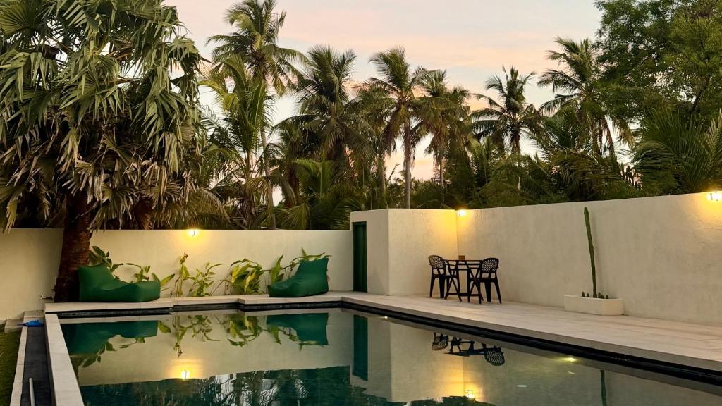 a villa with a swimming pool and palm trees at Nilaveli Boutique Hotel in Trincomalee
