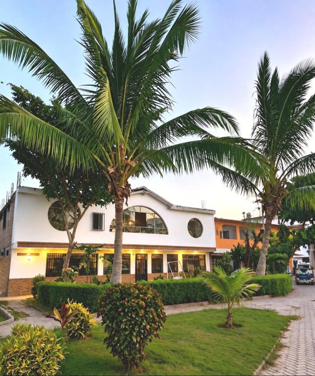 a building with palm trees in front of it at Hospedaje Cocos House Talara - amplias habitaciones, Buena Ubicacion in Talara