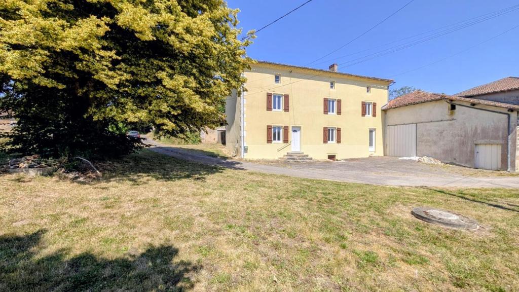 a large yellow building with a tree and a yard at Gîte de roger in Blond
