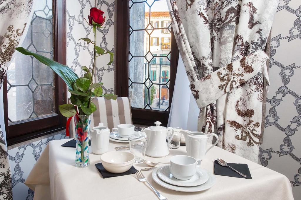 a table with a white table cloth and a rose in a vase at Hotel Ca' Nobile Corner in Venice