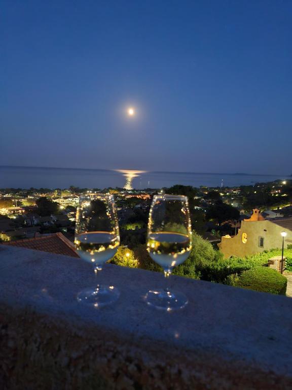 two wine glasses sitting on a ledge with a view at Panoramicissima in Costa Rei