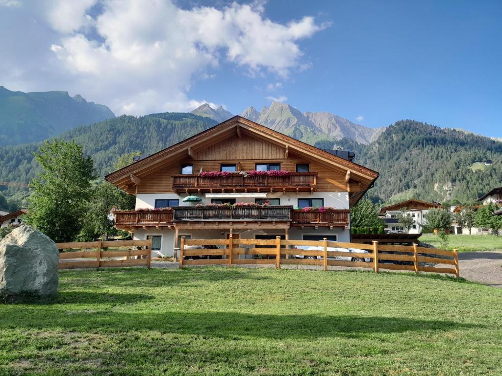 a house with a fence and mountains in the background at Oberrollerhof in Virgen