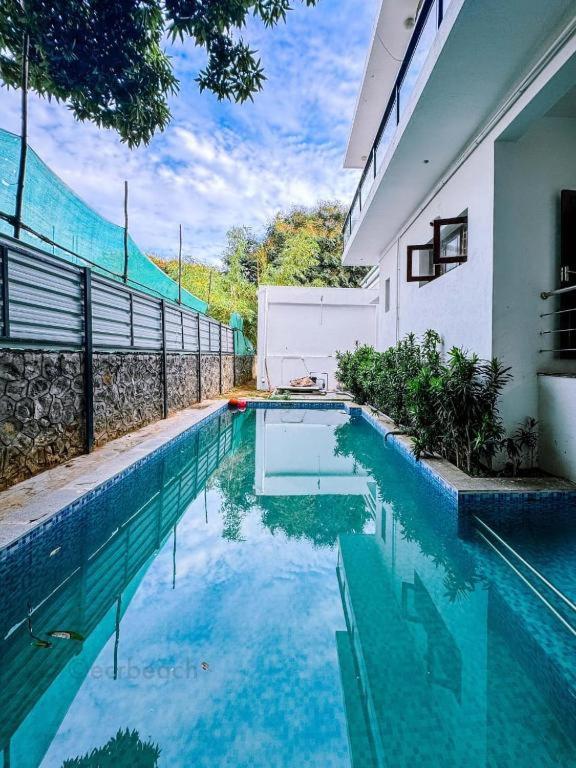 a swimming pool in front of a house at Hotel Sakthi-Pallava Shore's in Mahabalipuram