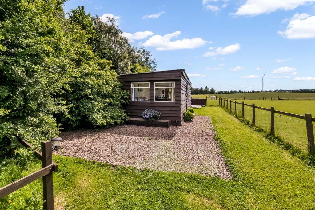a tiny house in a field with a fence at Farmer's Cabin in Forfar
