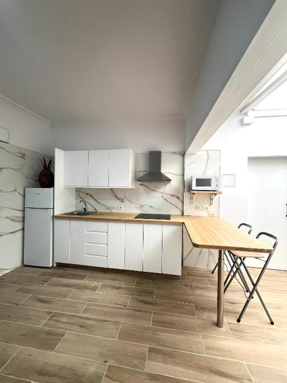 a kitchen with white cabinets and a wooden table at Teror Centro 1 in Teror