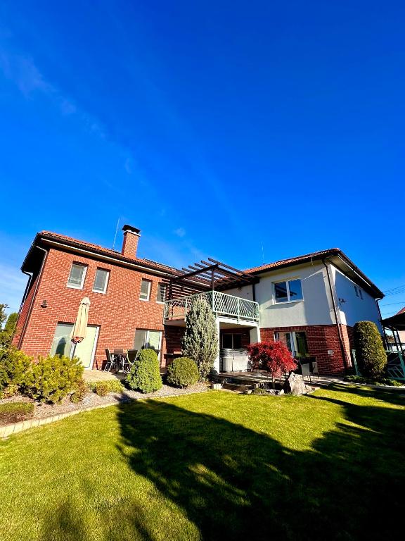 a large red brick house with a grass yard at Penzión Lili in Opatovce nad Nitrou