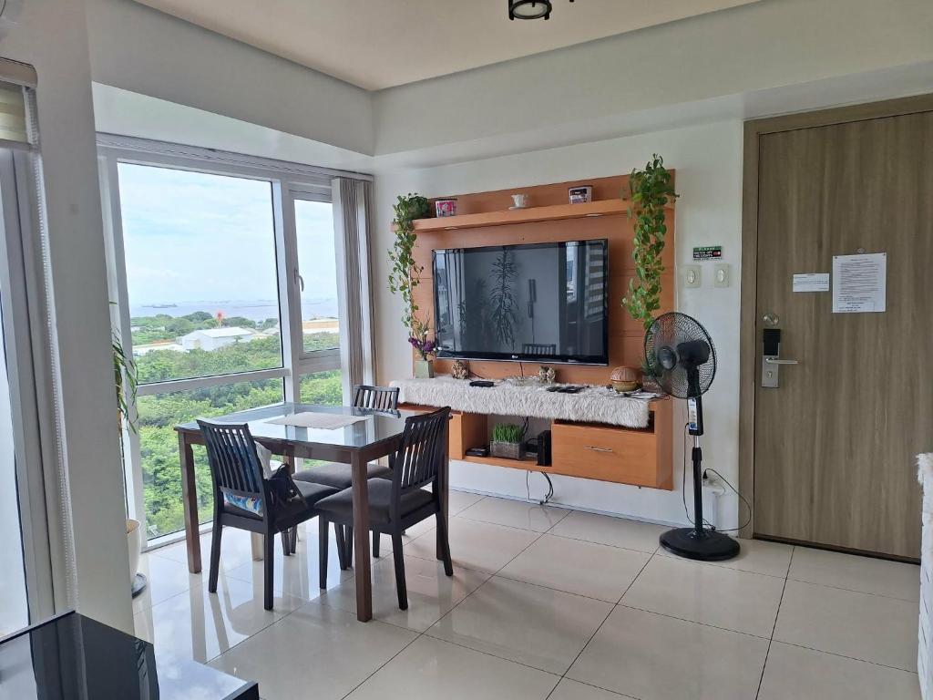 a dining room with a table and a television at De Luxe, Standard and Studio Suites -The Breeze Residences-close to Airport,Mall of Asia, US Embassy in Manila