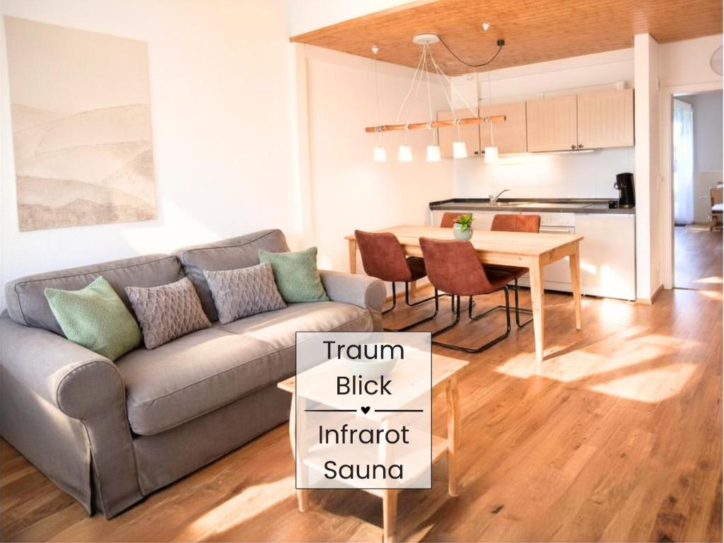 a living room with a couch and a table at SONNENSEITE Schonach - Private Infrarot-Sauna - Schwarzwald-Panoramablick - 2 separate Schlafzimmer - Ruhige Lage am Waldrand in Schonach