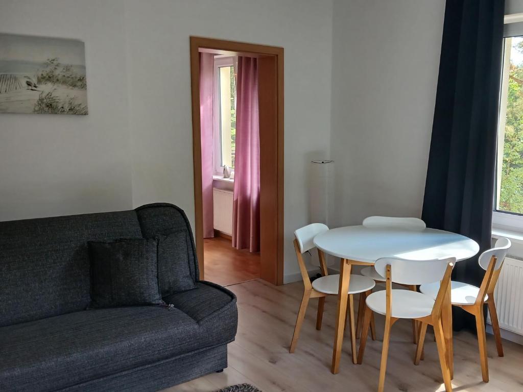 a living room with a couch and a table and chairs at Przy Lesie Apartamenty Pokoje Parking in Pobierowo