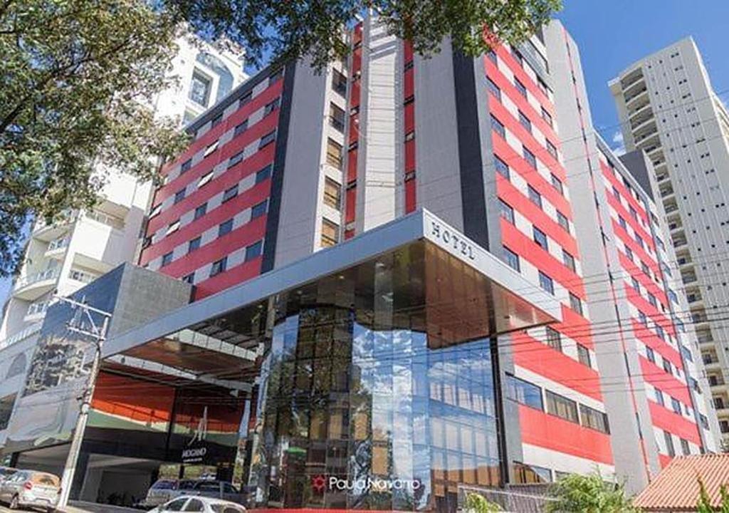 a tall building with a sign in front of it at Mogano Premium Hotel - ELETROPOSTO in Chapecó