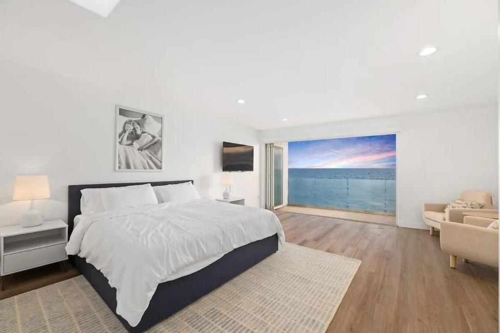 a white bedroom with a large bed and a couch at Malibu Beachfront Home with Rock Spa Ocean Views & Huge Deck in Malibu