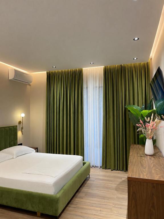 a bedroom with a large bed and green curtains at Olivium Rooms in Vlorë
