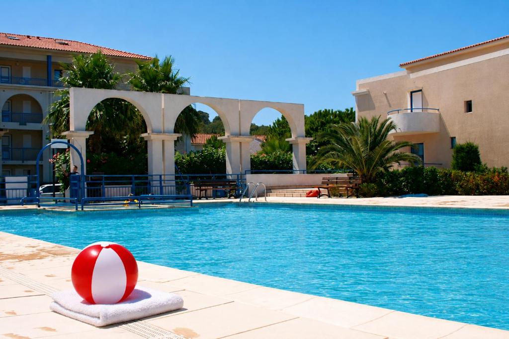 a swimming pool with a red ball in front of a building at Résidence d'Azur 2 311 appartement climatisé in Le Lavandou