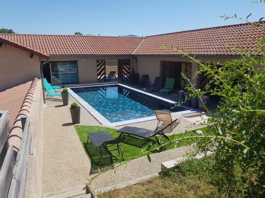 a swimming pool in the backyard of a house at Hôtel Les Rives D'Allier in Mazeyrat-d'Allier