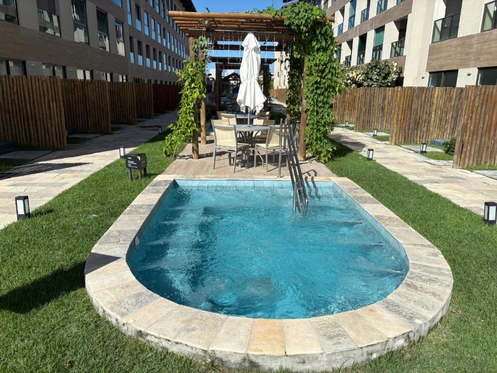 a swimming pool in a yard with a table and chairs at Flat na Praia dos Carneiros - Resort Max Carneiros Suítes in Tamandaré