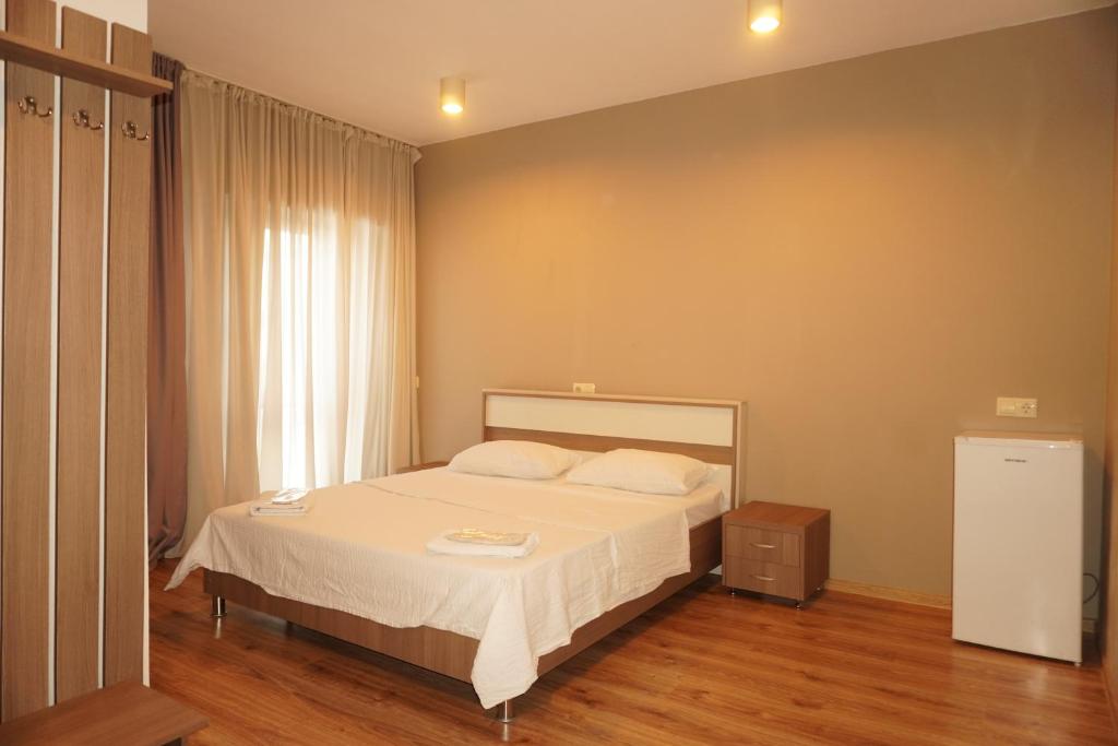 a bedroom with a bed with white sheets and a window at Hotel PM Palace in Nizhnyaya Alekseyevka