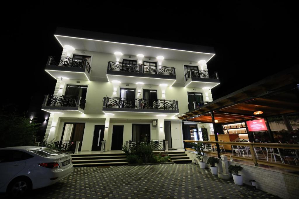 a white building with two balconies and a car parked in front at LiEl Holiday in Vlorë