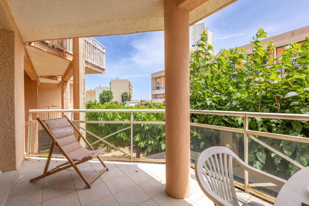a balcony with two chairs and a view of the city at Valras-Loc - T2 Piscine Terrasse in Valras-Plage