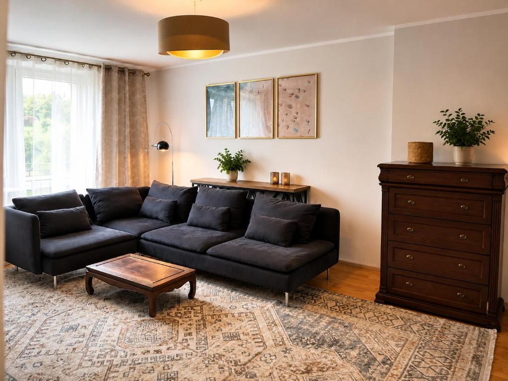 a living room with a black couch and a table at Nine to Trail Apartment in Wielka Wieś