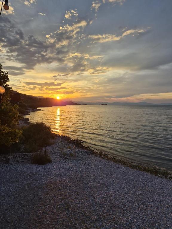 a sunset over a body of water with the sun setting at ROOMS balani in Shkodër