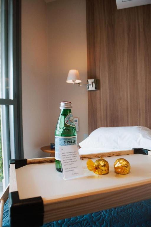 a bottle of soda sitting on a table next to a bed at Studio Moderno A 2 mim do Metrô Sacomã Wi-Fi 600mb | SP Expo in São Paulo
