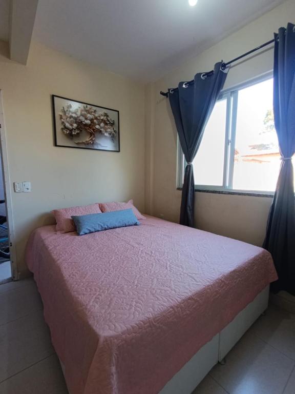 a bedroom with a pink bed with a window at Apartamento Castelhanos Anchieta in Anchieta