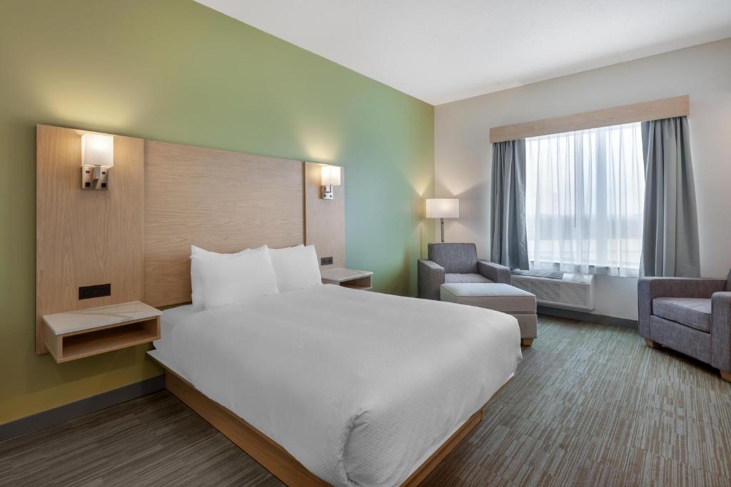 a hotel room with a large white bed and chairs at Best Western Plus Kawartha Lakes Hotel & Suites in Lindsay