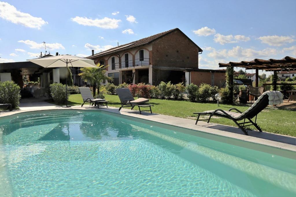 a swimming pool with two chairs and a house at Casale del Miglio in Casorzo