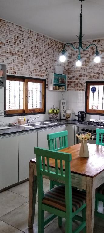 a kitchen with a wooden table and green chairs at Hospedaje El Ciruelo in Alta Gracia