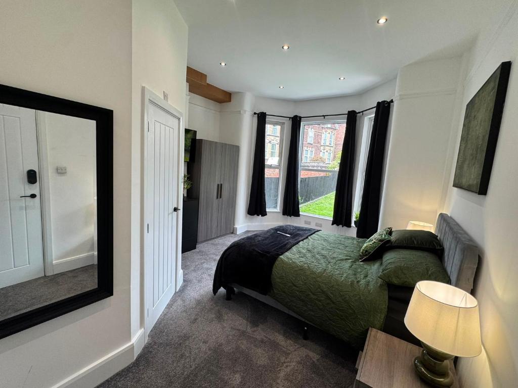 a bedroom with a bed and a lamp and windows at The Carlton Collection in Birkenhead