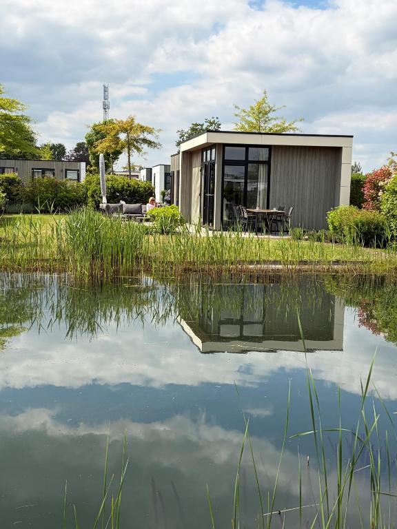 a small house next to a body of water at Casa-MiU am Wasser - Olburgen - perfekt für Familien - mit Freibad, Sauna, Restaurant und Spielplatz in Olburgen