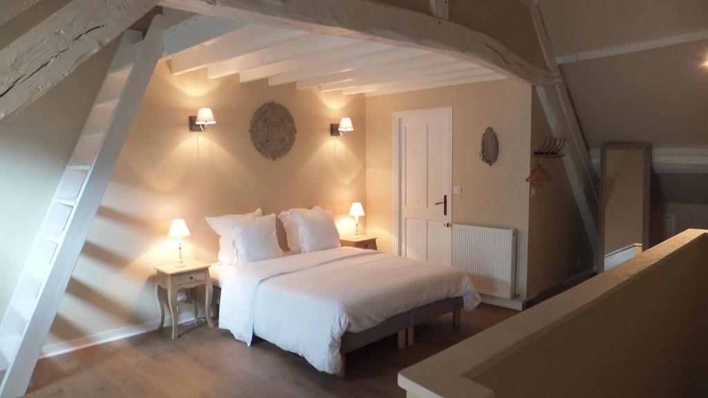 a bedroom with a white bed and two night stands at Hotel La Closeraie in Sully-sur-Loire