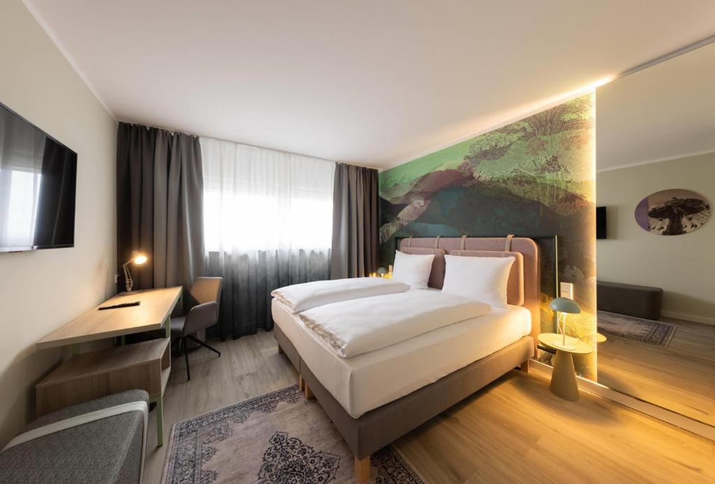 a hotel room with a bed and a desk at The Rilano Hotel Munich, Trademark Collection by Wyndham in Munich