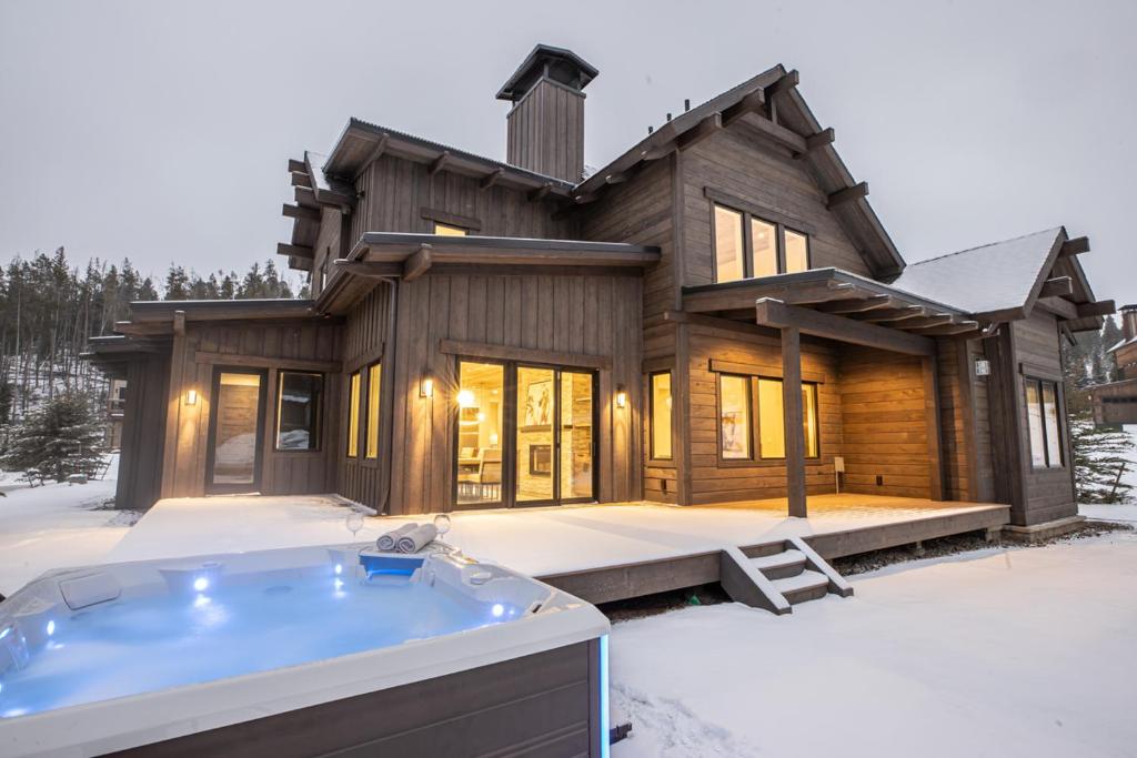 a house with a hot tub in the snow at Spanish Peaks - Highlands Cabin 45 in Big Sky