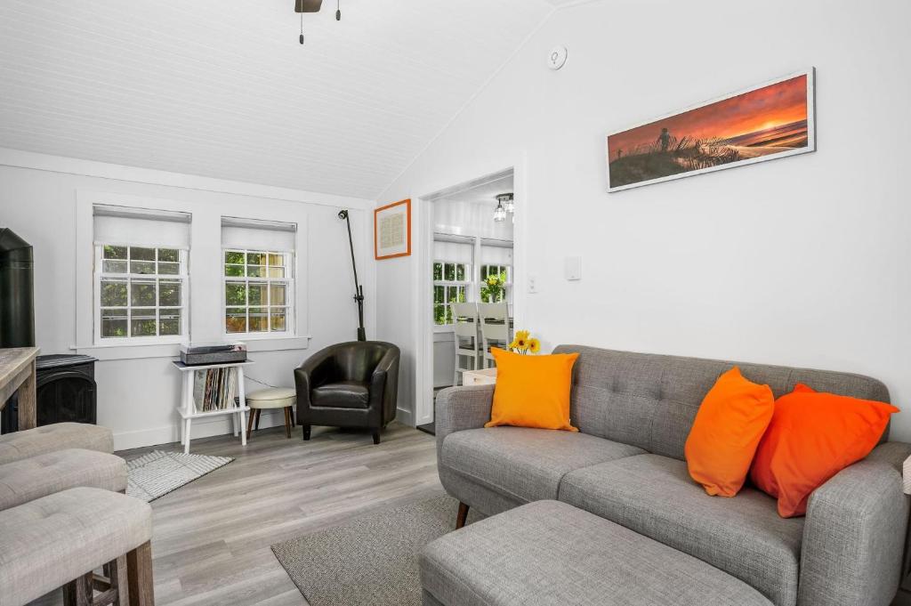 a living room with a gray couch and orange pillows at Bed, Splash Beyond – Coastal Comfort Awaits in Orleans