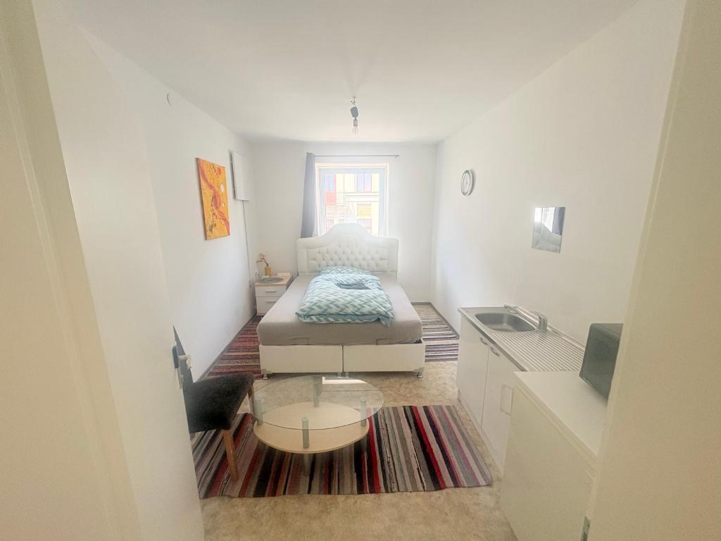 a small white room with a bed and a table at Beenie 1 in Linz