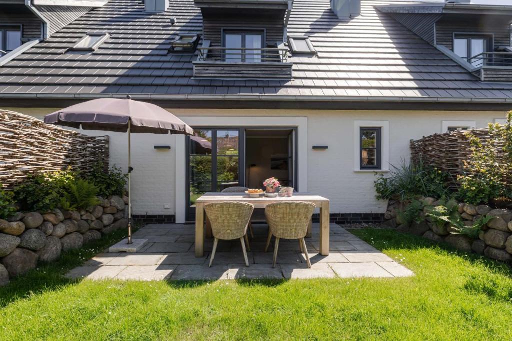 a table with chairs and an umbrella in a yard at Meersalz in Tinnum