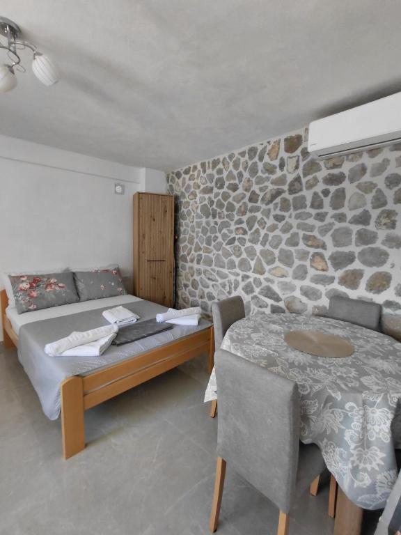a bedroom with a bed and a table and a stone wall at Anastasija & Tara in Ðuraševići