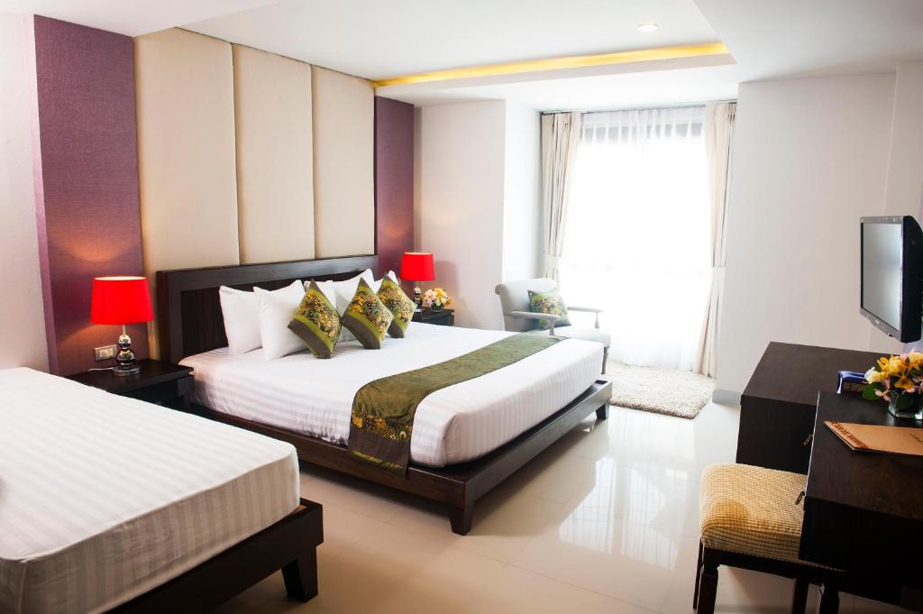 a hotel room with two beds and a television at Montien House - SHA Plus in Chaweng