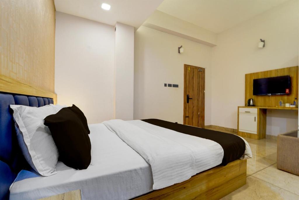 a bedroom with a bed with white sheets and a television at Hotel O by OYO REFRESH INN & SUITES in Kozhikode