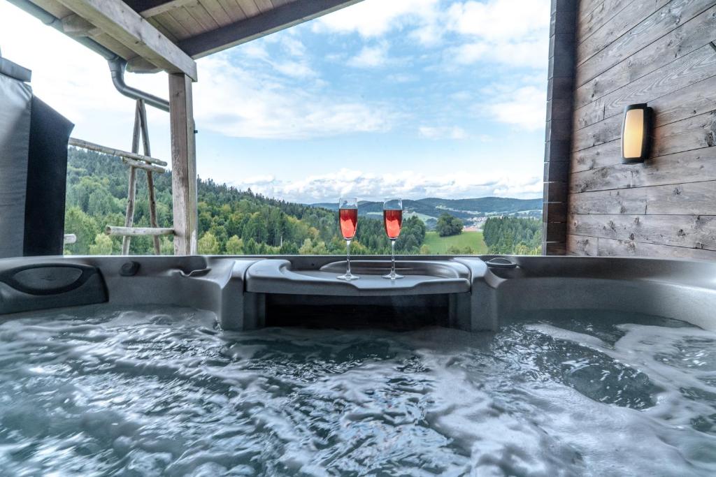 a jacuzzi tub with two wine glasses in it at 5 Sterne Holzchalet Dienberger Hof in Untergriesbach