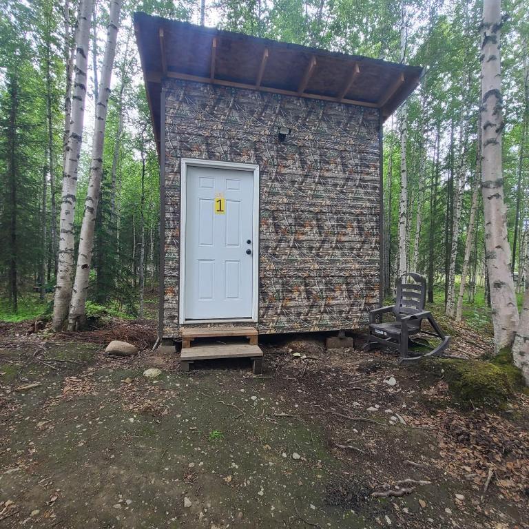a small brick building with a white door and a chair at Ma-Su Thunder Cabin #1 in Houston