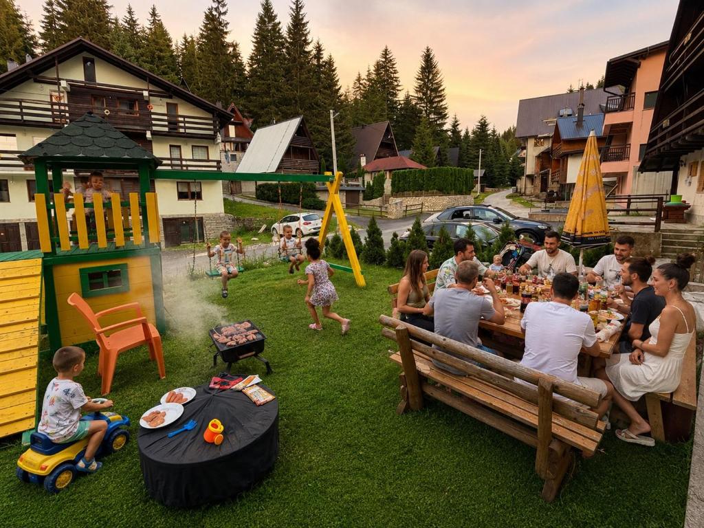 a group of people sitting around a table in a yard at Alpin Wellness & Spa Vlašić in Vlasic