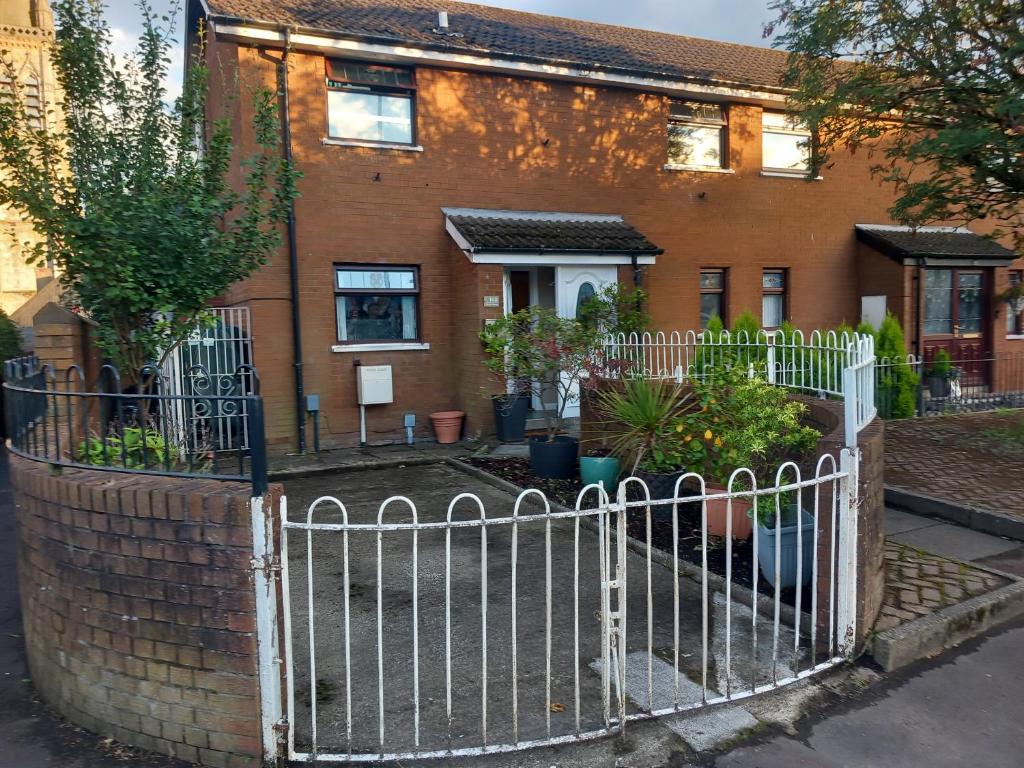 a white fence in front of a brick house at Divis street guest house in Belfast