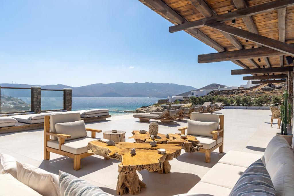 a patio with a table and chairs and the ocean at Mykonos Panormos Villas & Suites in Mykonos