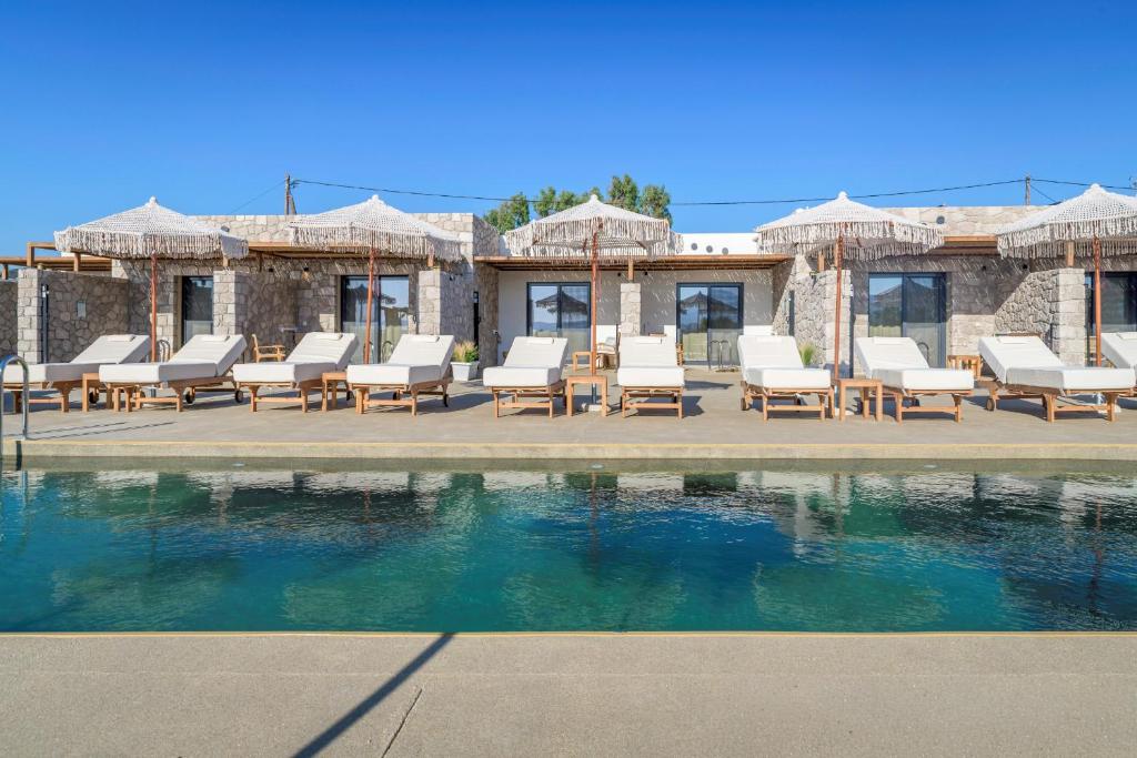 a swimming pool with lounge chairs and a house at Zefyria Luxury Suites in Zefiría