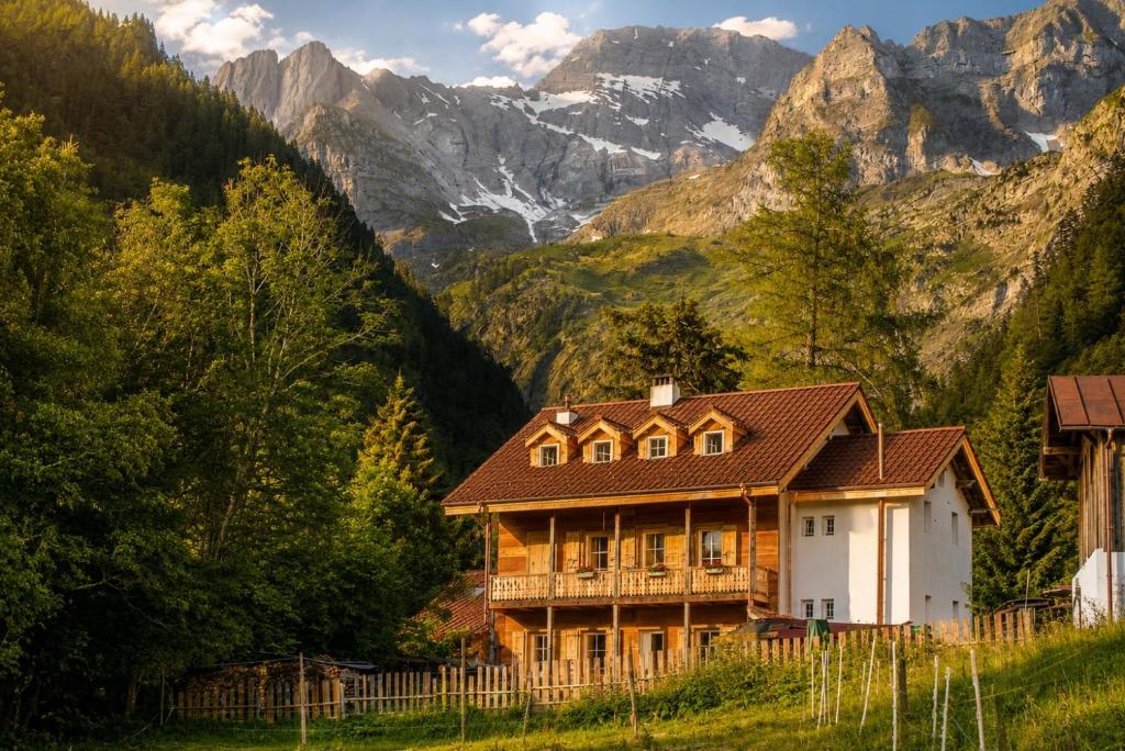 a house on a hill with mountains in the background at Riversong Centre Thermal in Les Plans-sur-Bex