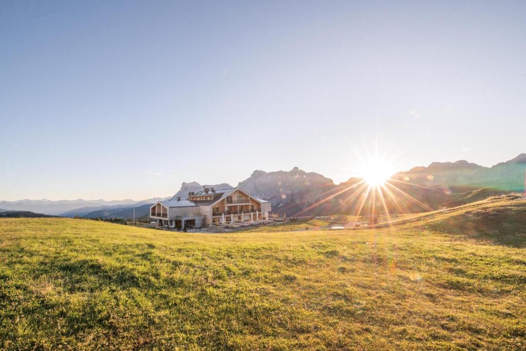 a house on a hill with the sun setting at Rifugio Alpino Pralongià in Corvara in Badia