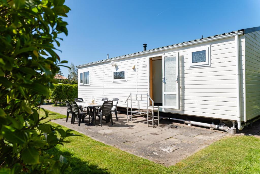 a white tiny house with a table and chairs at chalet de kievit in Serooskerke