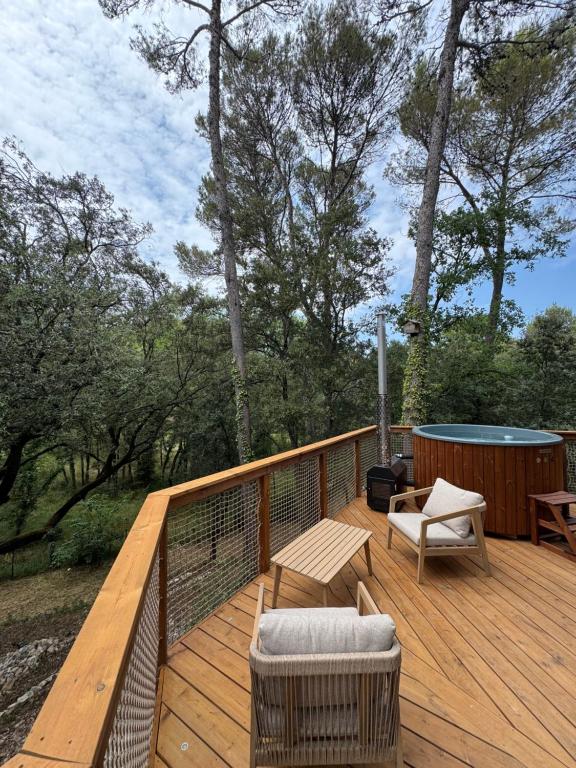 a wooden deck with a bench and chairs on it at Domaine d'Olga - Lodges & SPA in Aniane